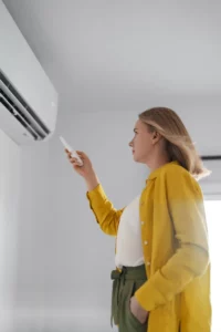 Femme qui règle un climatiseur avec une télécommande